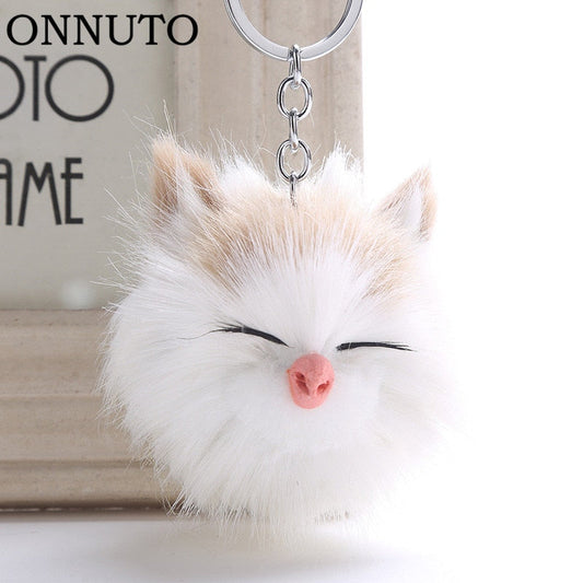 Lindo llavero con pompón de gato sonriente durmiendo